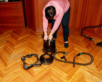 A middle-aged woman collects a vacuum cleaner for house cleaning.