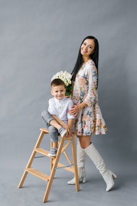 Portrait of a young mother with a small child standing on a gray background, family love 