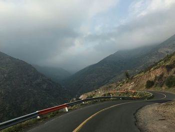 Mountain road against cloudy sky