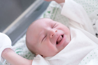 Cute baby boy crying while sleeping on bed