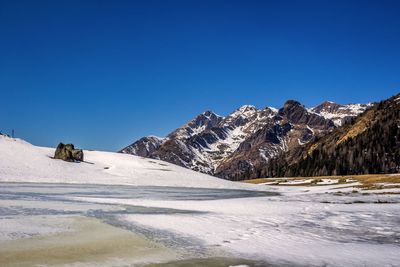 Scenic view of snowcapped mountains against clear blue sky