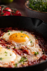 Breakfast with shakshouka and vegetables on a wooden table close up image