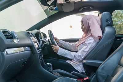 Side view of woman driving car