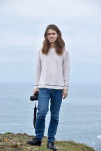 Portrait of man standing on cliff against sea