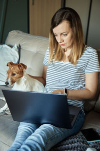Woman working from home with pet dog, using laptop