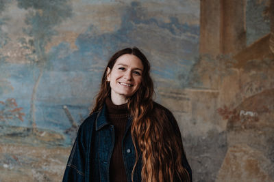 Portrait of young woman standing against wall