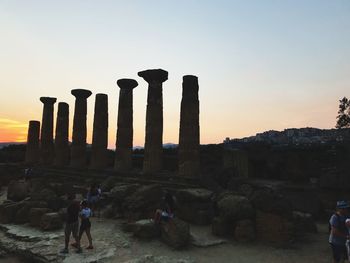People at old ruin against sky during sunset
