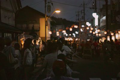 Group of people walking on illuminated street at night