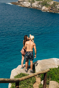Rear view of shirtless man looking at sea