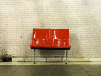 Empty red seats against wall at subway station