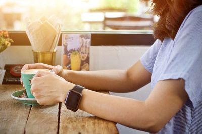 Midsection of woman sitting on table at cafe