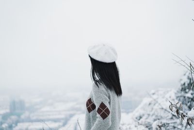 Rear view of woman in snow against clear sky