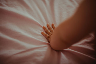 Cropped hand of baby boy on bed