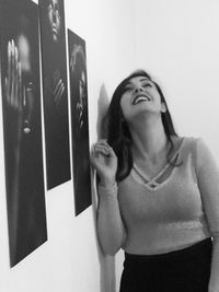 Portrait of young woman standing against wall at home