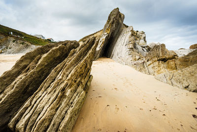 Rock formation on beach against sky