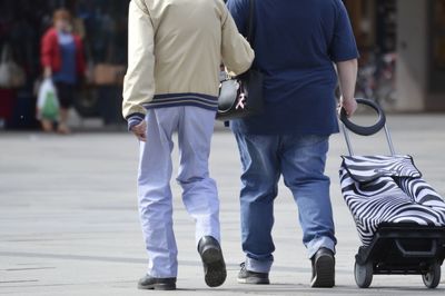 Rear view of people with luggage walking on street