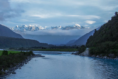 Scenic view of river and mountains against cloudy sky