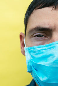 Young man wearing a mask on a yellow background