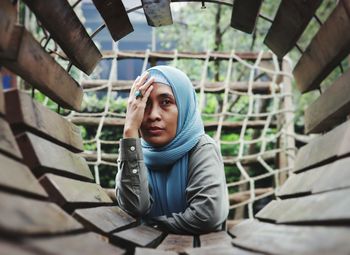 Low angle view of young woman sitting on railing