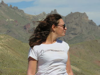 Beautiful young woman standing on mountain against sky