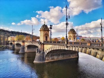 Arch bridge over river against sky in city