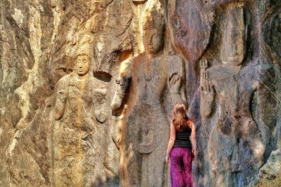 Rear view of woman looking carvings at buduruvagala