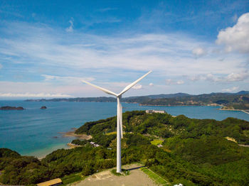 Windmills by sea against sky