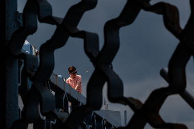 Man against sky seen through fence