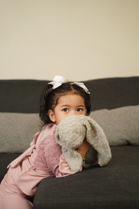 Portrait of cute baby girl sitting on sofa at home