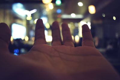 Close-up of hands against illuminated lights at night