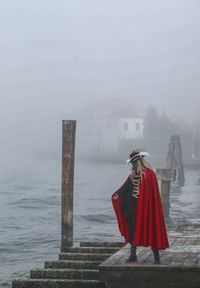 Woman in costume standing on pier during extreme weather