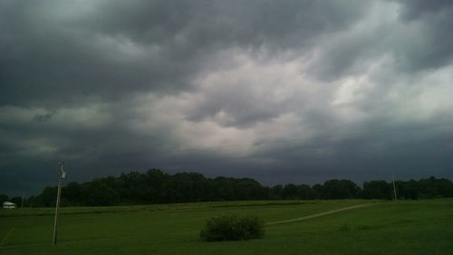 Scenic view of grassy field against cloudy sky