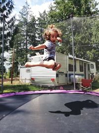 Full length of boy jumping against trees