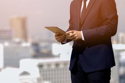Midsection of businessman holding digital tablet outdoors