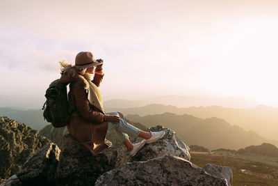 Man on rock in mountains against sky