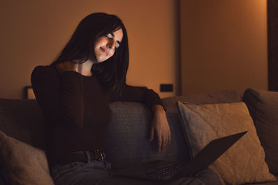 Young woman sitting on sofa at home