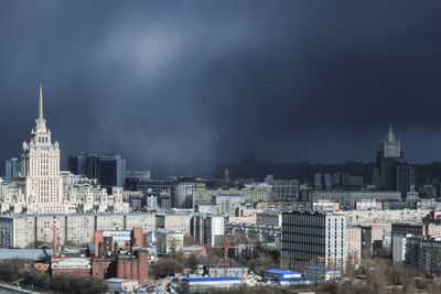 Buildings in city against stormy sky
