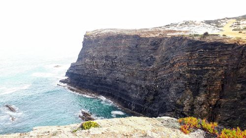 Rock formations by sea against clear sky