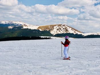 Woman on skiing on snow covered field against sky