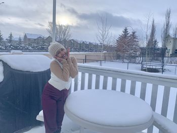 Woman standing in snow against sky during winter