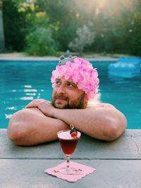 Drink by smiling man in swimming pool