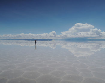 Mid distance view of woman standing on shore against sky