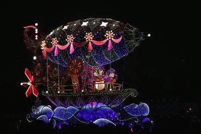 Low angle view of illuminated lighting equipment against black background
