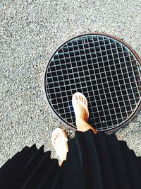 Low section of woman standing on manhole in street