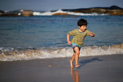 Full length of boy running at beach
