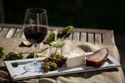 Close-up of red wine and cheese on wooden table