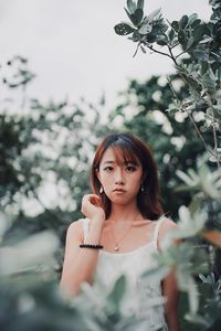 Portrait of beautiful young woman standing by plants