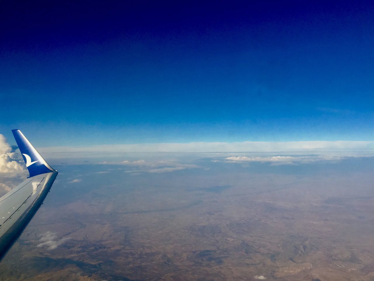 AERIAL VIEW OF AIRPLANE WING AGAINST SKY