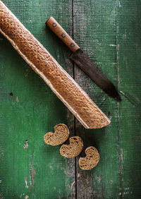 Directly above shot of bread loaf and knife on old green table