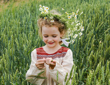 Smiling girl wearing flowers standing on field